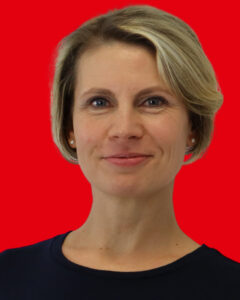 Portrait SPD-Stadträtin Anne-Kathrin Findeiß vor rotem Hintergrund.