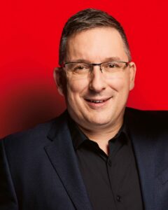 Portrait SPD-Stadtrat Jens Jurschka vor rotem Hintergrund.